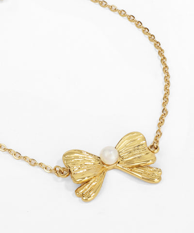 Gold bow-shaped necklace with a pearl on a white background