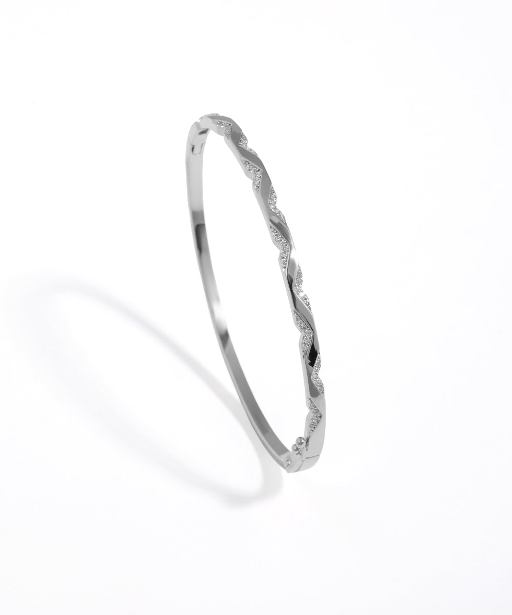 Silver bangle with twisted design on a white background