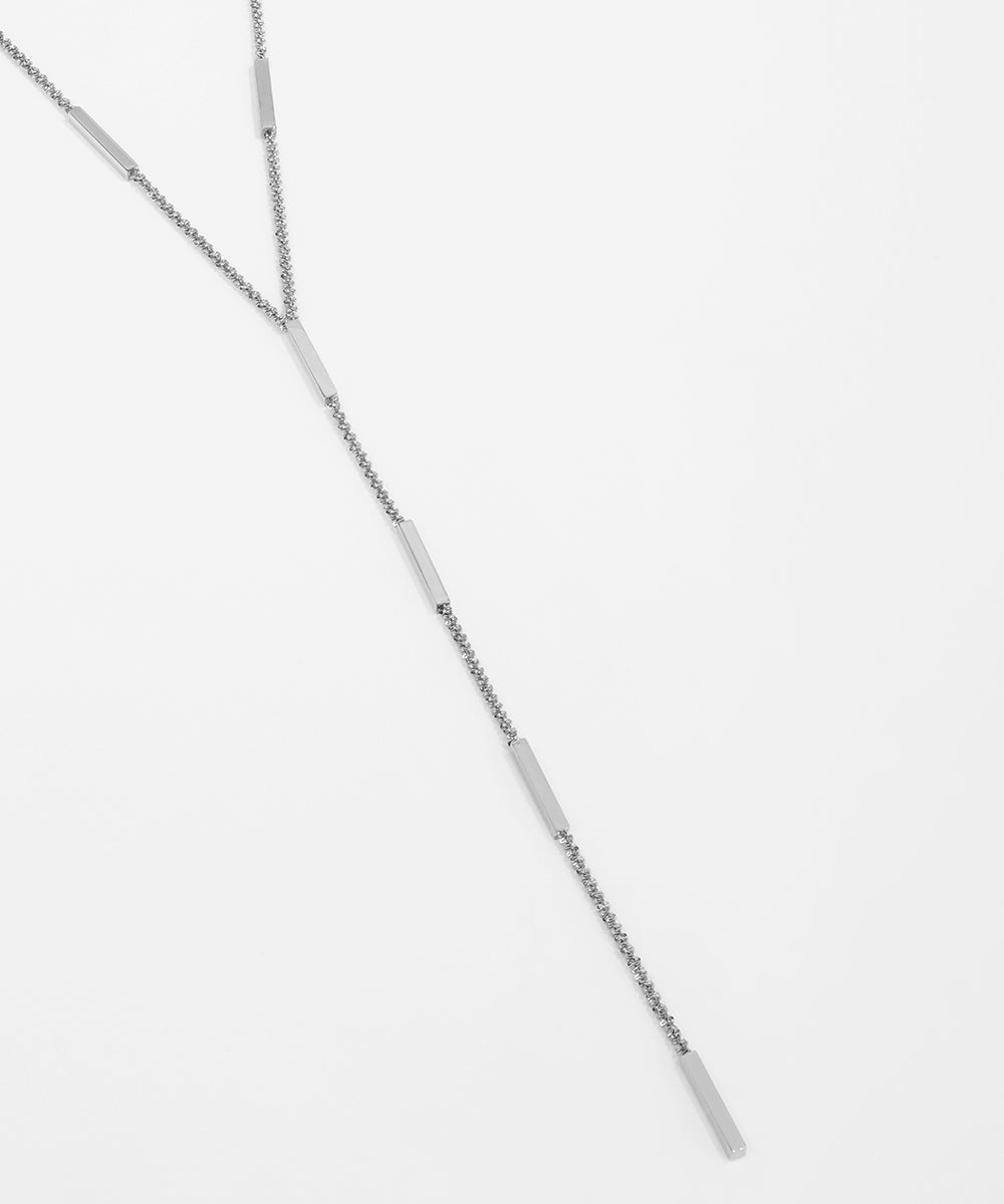 Silver necklace on a light gray background