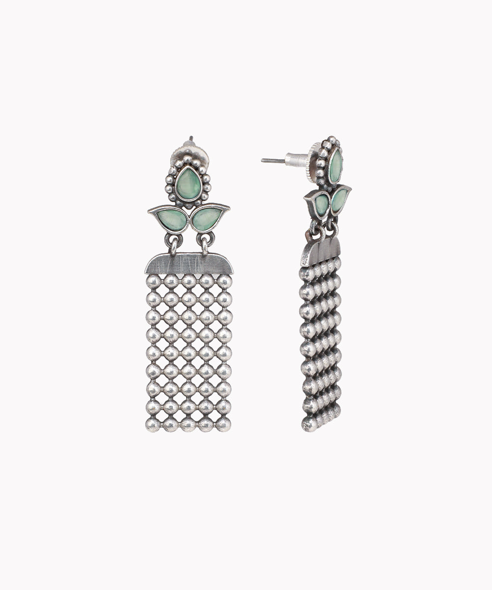 Pair of silver tassel earrings with green gemstones on a white background