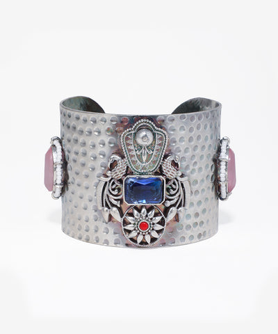 Decorative cuff bracelet with blue gemstone and intricate design on a white background