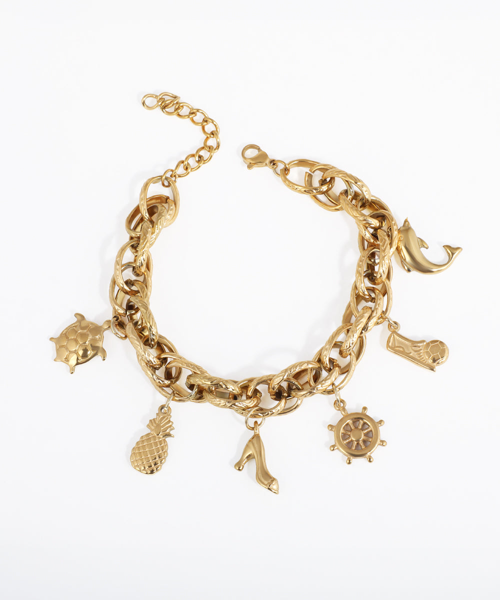 Gold-tone chunky link chain bracelet with multiple charms including a dolphin, turtle, pineapple, high heel, and ship's wheel.