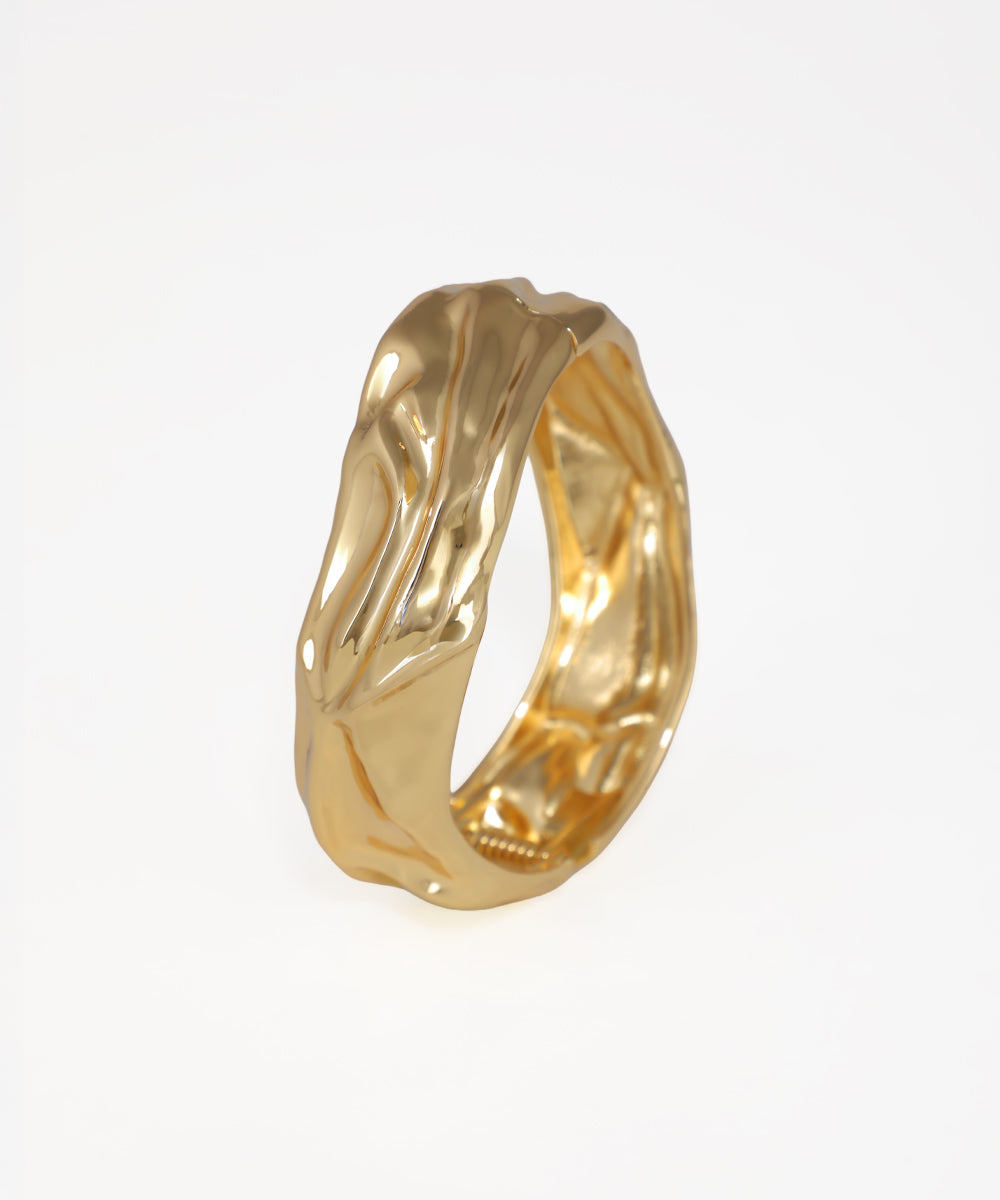Gold ring with a textured design on a white background