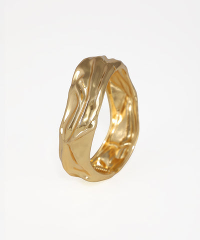 Gold ring with a textured design on a white background