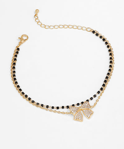 Bracelet with black beads and gold bow charm on a white background