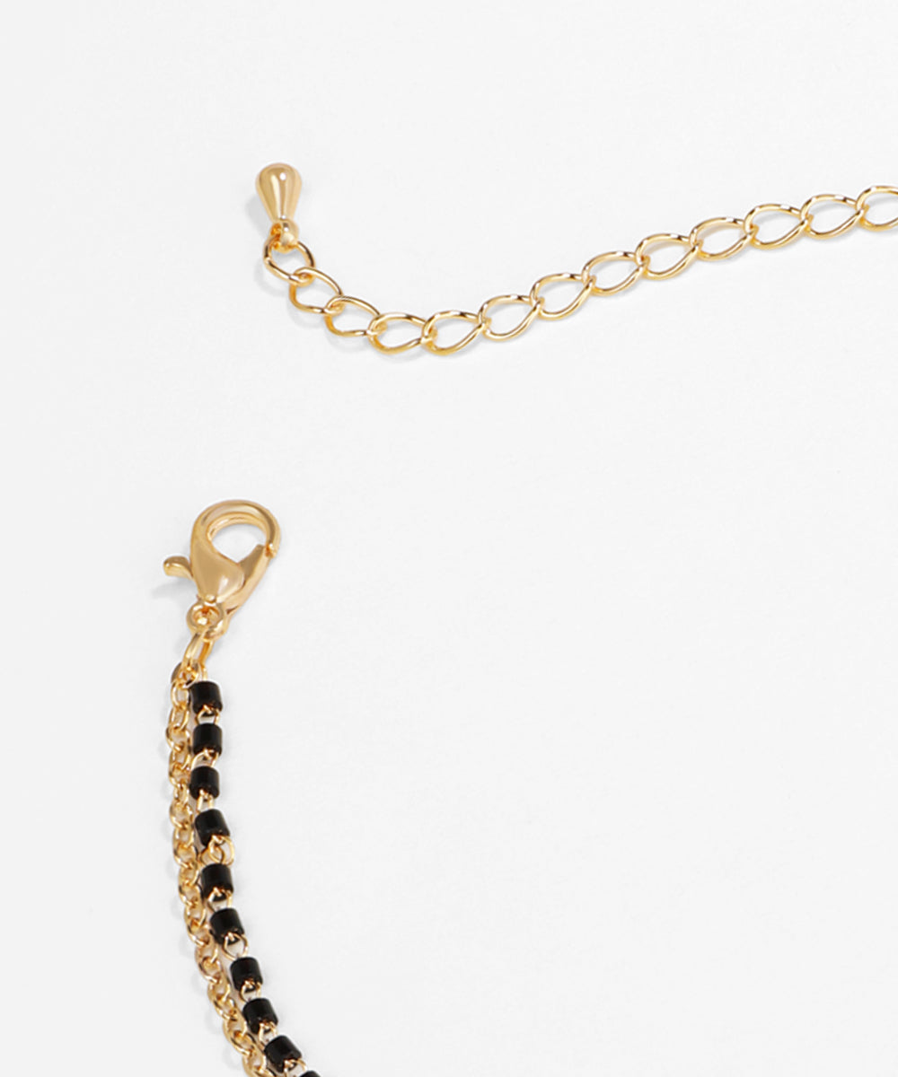 Gold bracelet with black beads on a white background