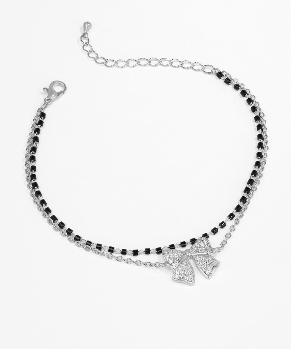 Bracelet with black and clear beads and a silver bow charm on a white background