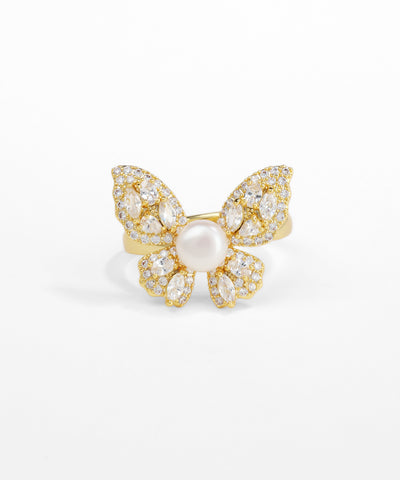 Gold butterfly-shaped ring with a pearl center on a white background