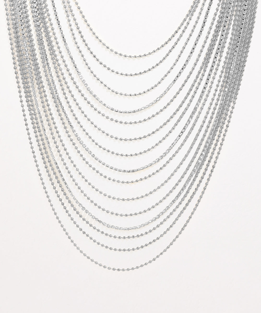 Multiple silver necklaces stacked on a light gray background