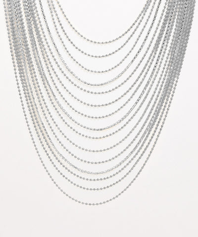 Multiple silver necklaces stacked on a light gray background