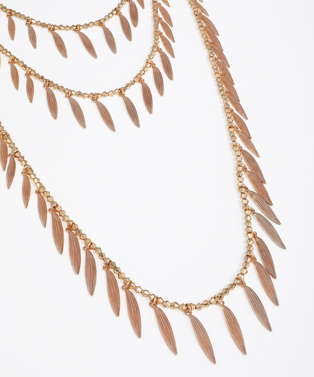 Rose gold necklace with leaf-like pendants on a white background