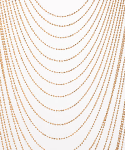 Multiple strands of gold beads on a white background