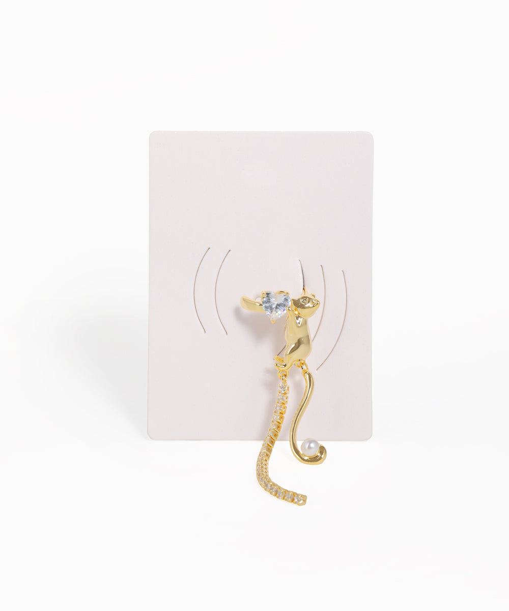 Gold cat-shaped earring on a white card with a white background
