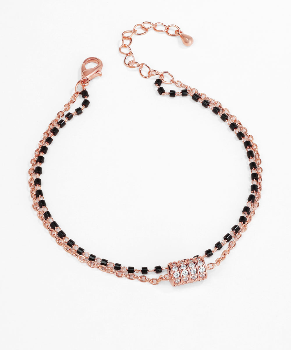 Rose gold bracelet with black beads on a white background