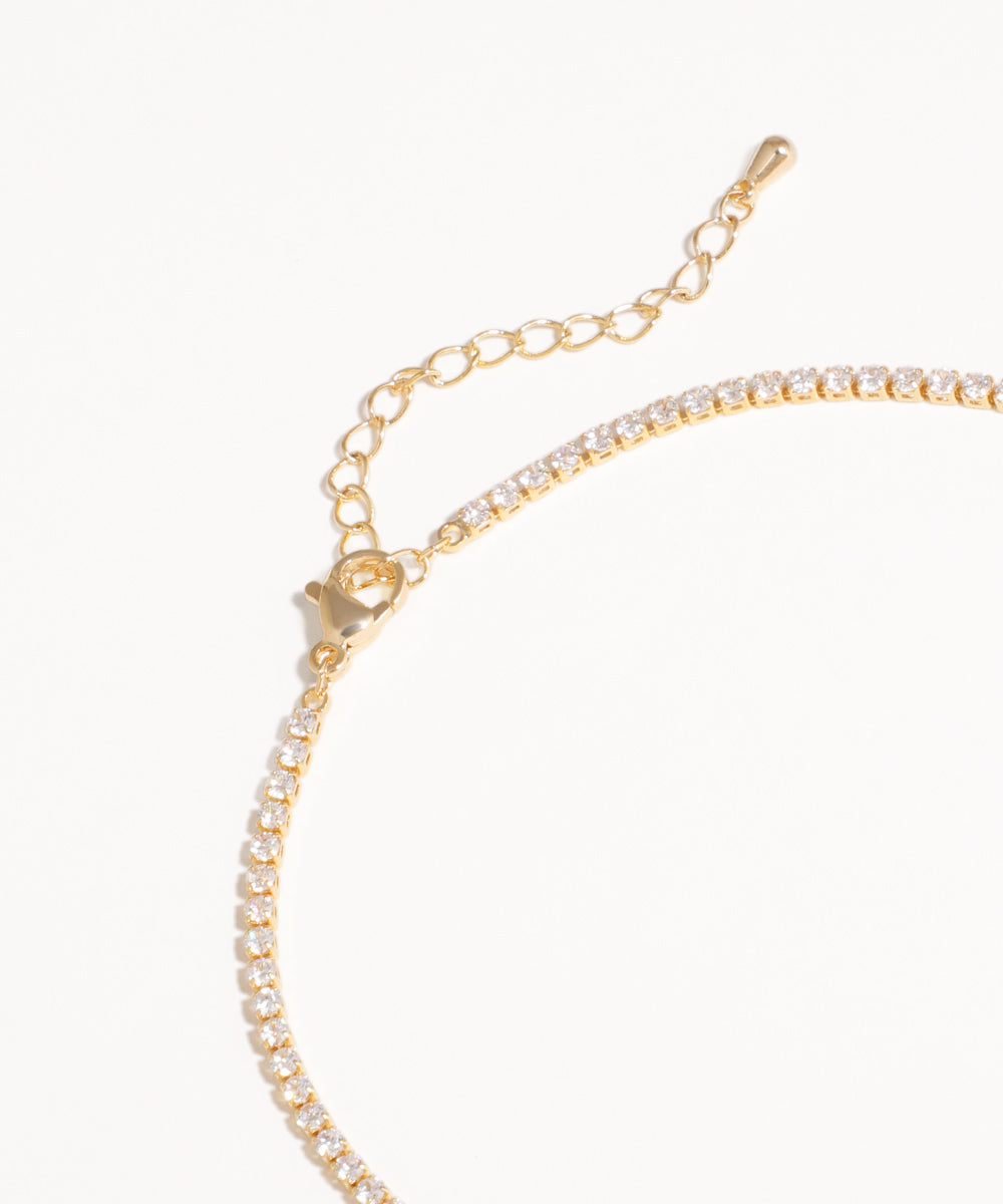 Gold bracelet with clear stones on a white background