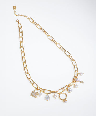 Gold-tone necklace with paperclip chain and assorted charms including lock, key, ring, CZ, and faux pearls.