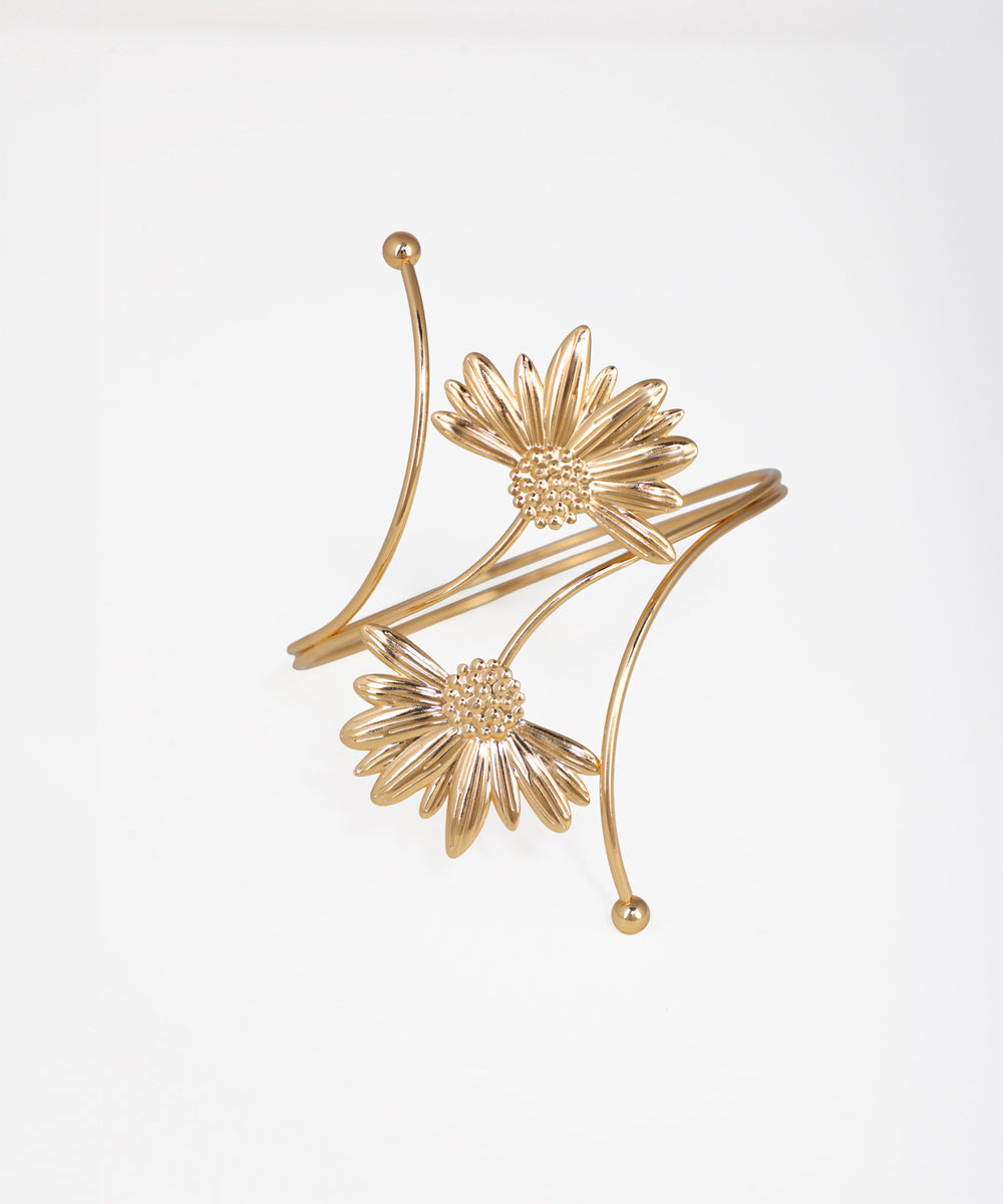 Gold floral earrings on a light gray background