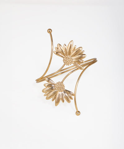 Gold floral earrings on a light gray background