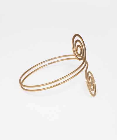 Gold spiral bracelet on a light gray background