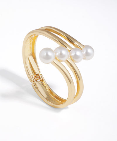 Gold bracelet with three pearls on a white background