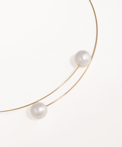 Gold necklace with three pearls on a white background