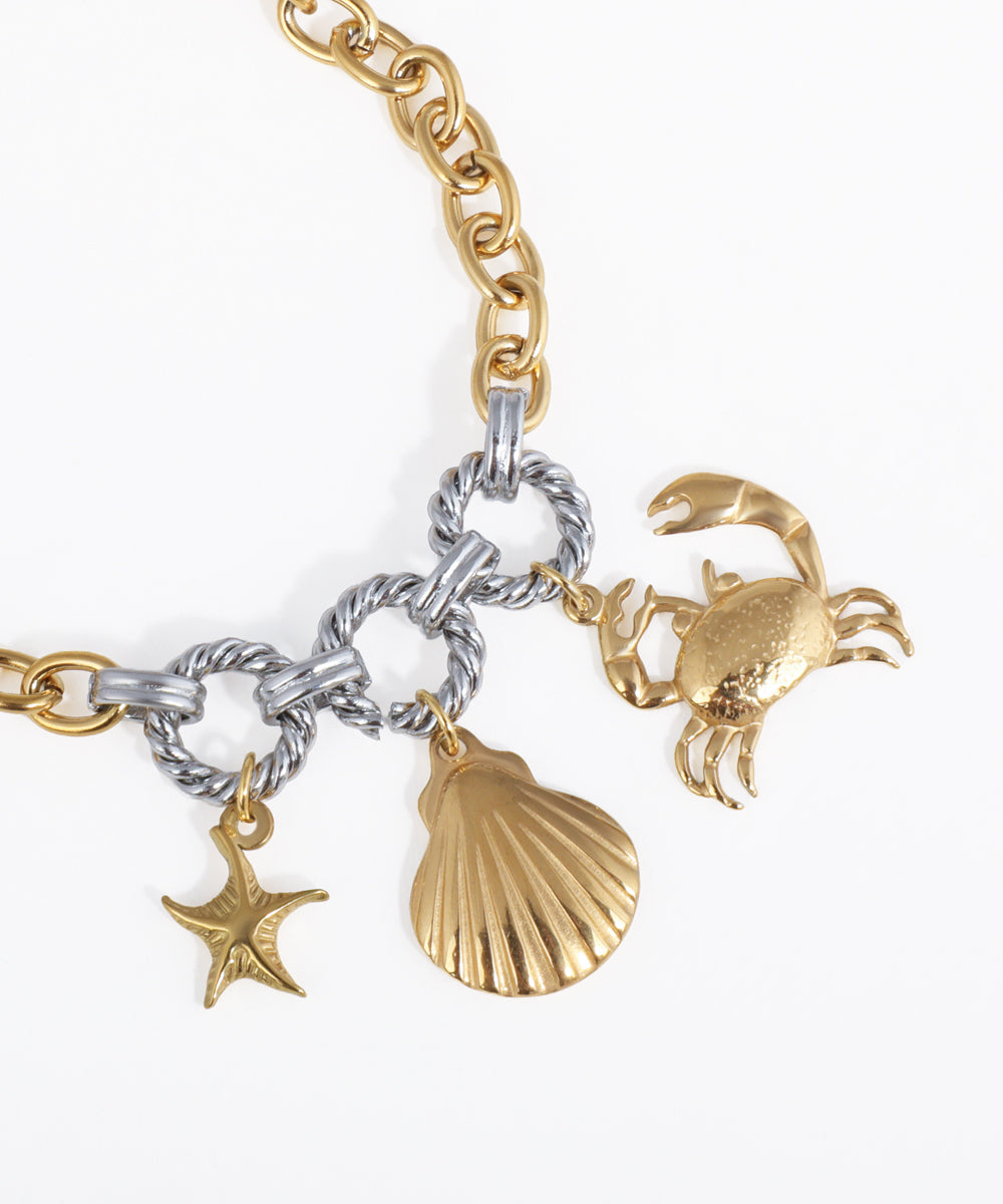 Gold and silver bracelet with starfish, shell, and crab charms on a white background