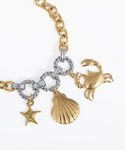 Gold and silver bracelet with starfish, shell, and crab charms on a white background