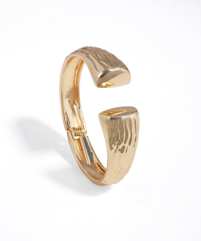 Gold-tone bangle bracelet with a sculpted, open design and textured finish