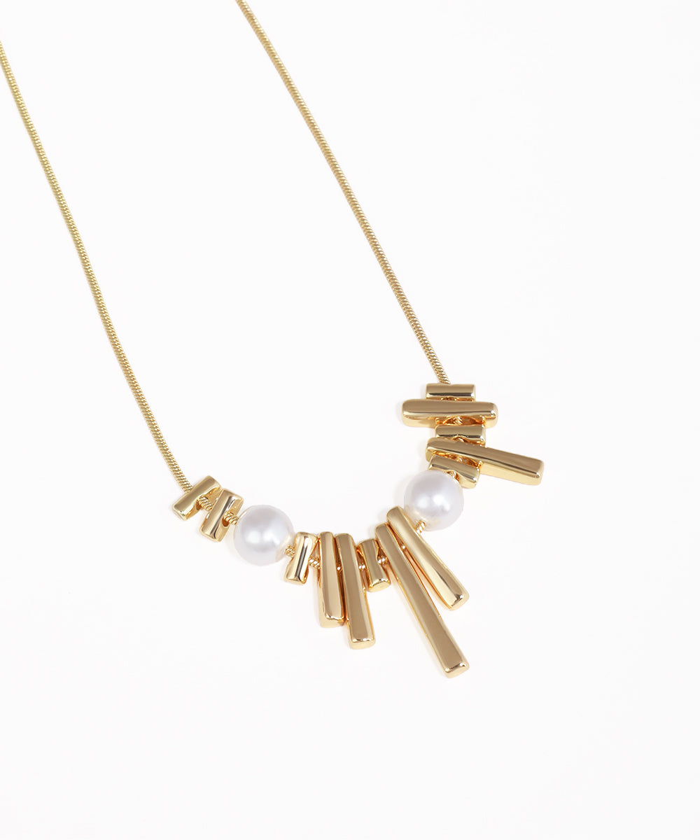 Gold necklace with bar and pearl pendant on a white background