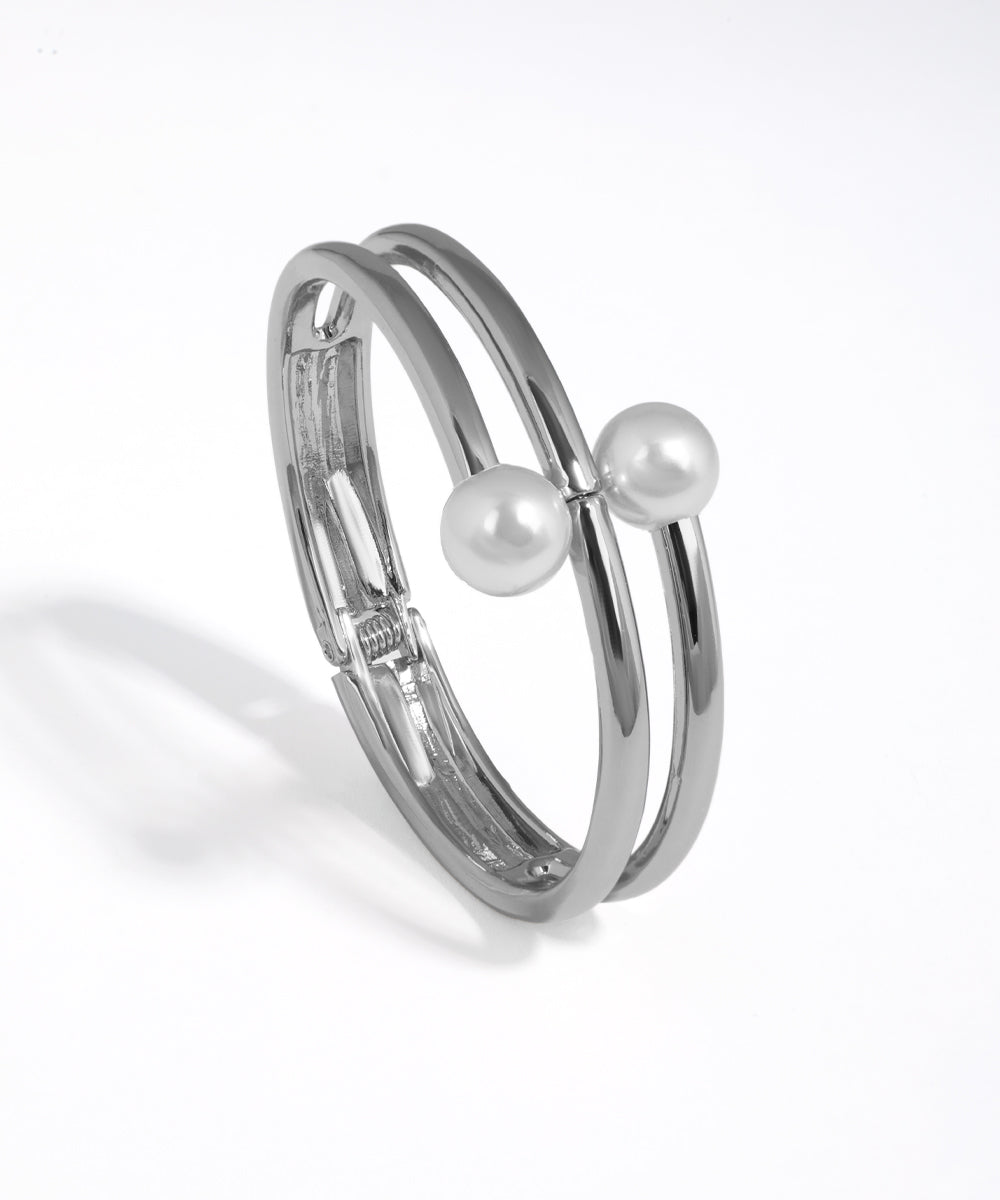 Silver bracelet with two pearls on a white background