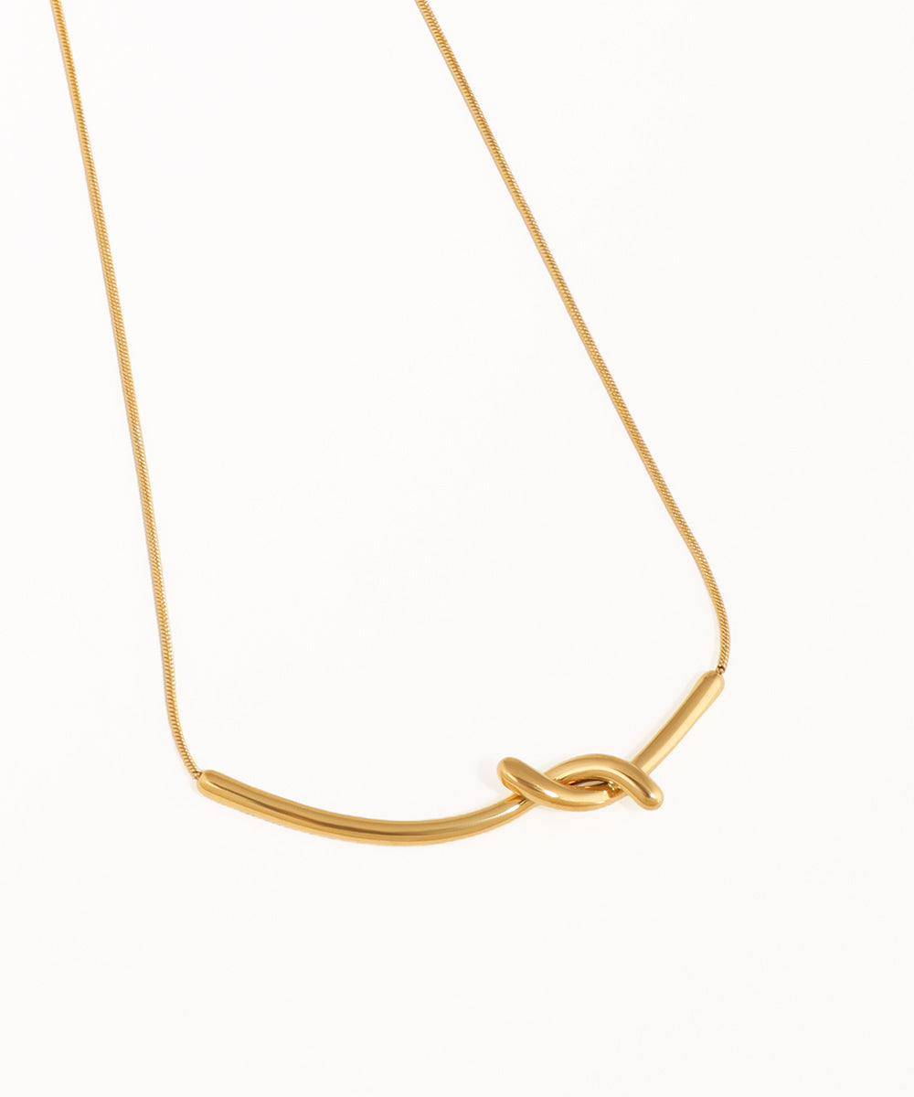 Gold necklace with a knot design on a white background