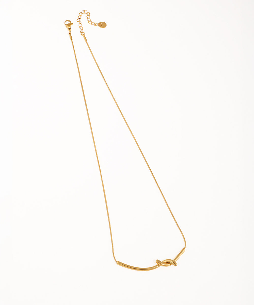 Gold-tone necklace with a central bar forming a sculptural knot design on a fine snake chain.