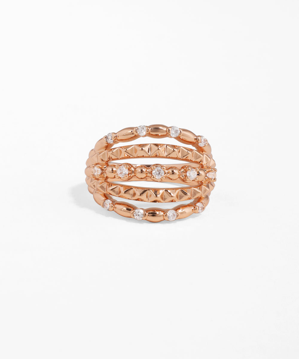 Rose gold stackable rings with embedded stones on a white background