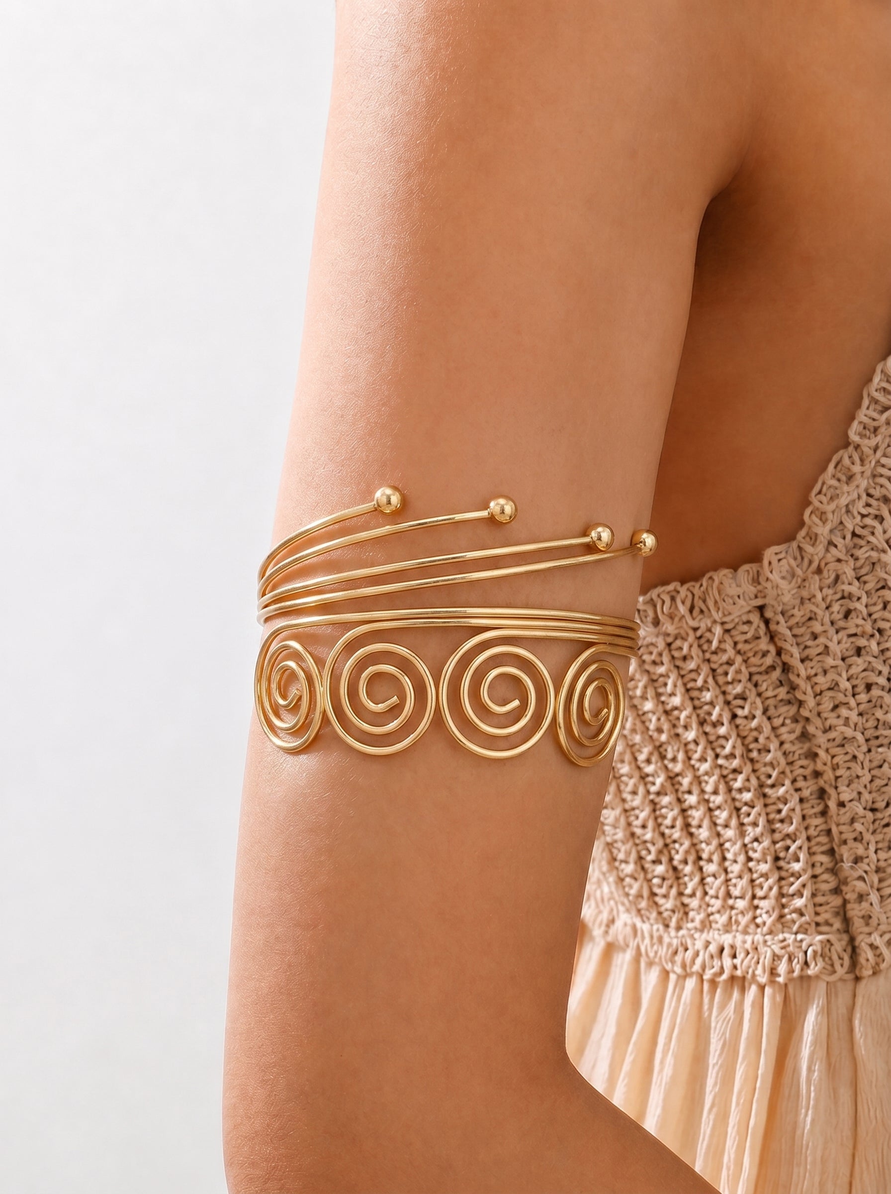 Gold arm band on a person's arm with a plain background