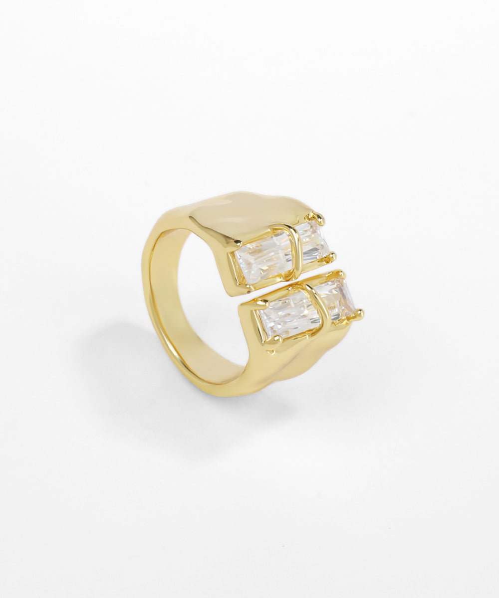 Gold ring with emerald-cut gemstones on a white background