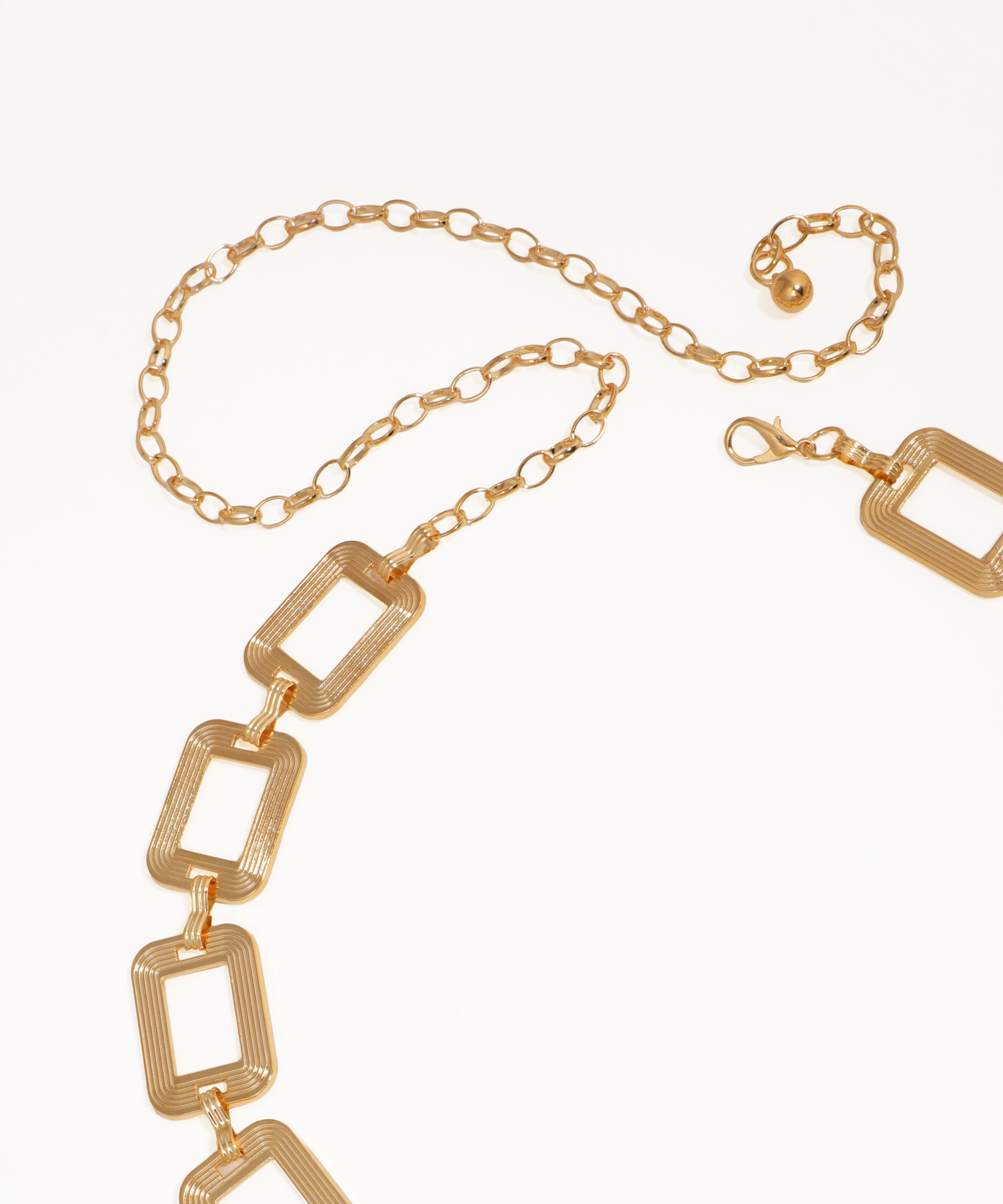 Gold chain necklace with geometric links on a white background