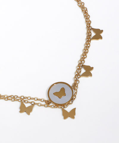 Gold butterfly charm necklace on a white background