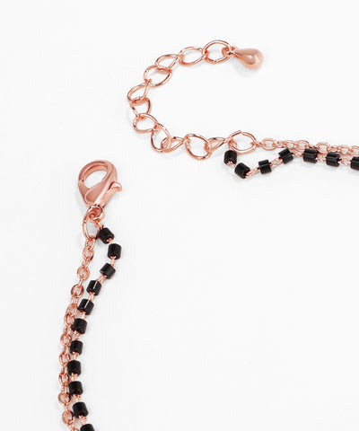 Rose gold and black beaded bracelet on a white background