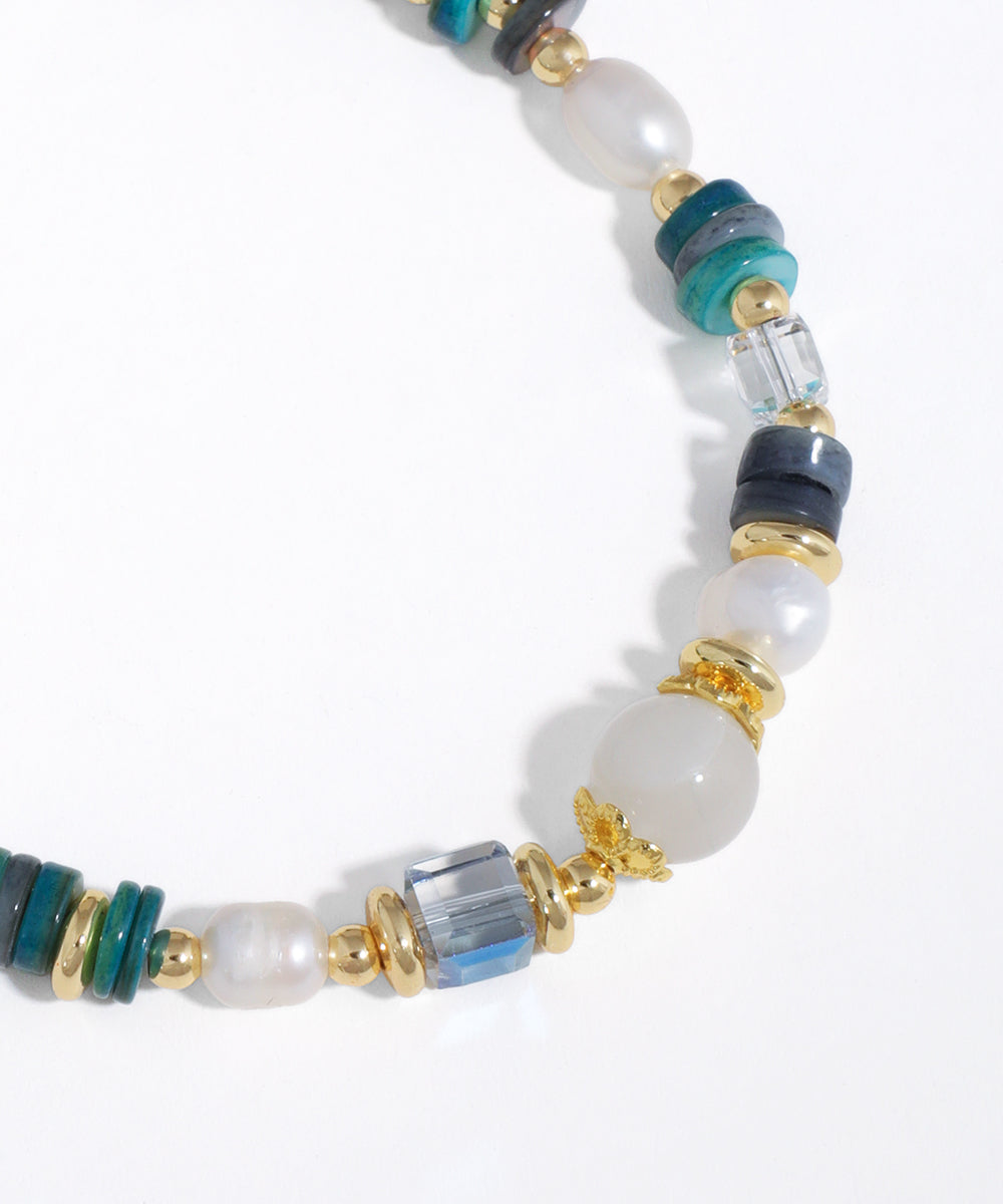 Close-up of a beaded necklace with pearls, turquoise, and gold elements on a white background