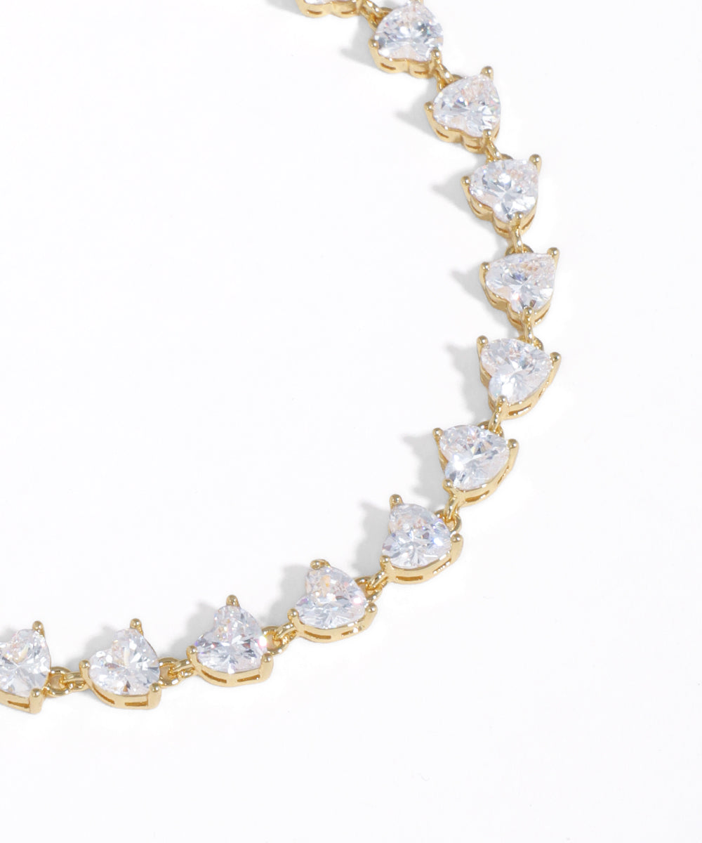 Gold bracelet with clear gemstones on a white background