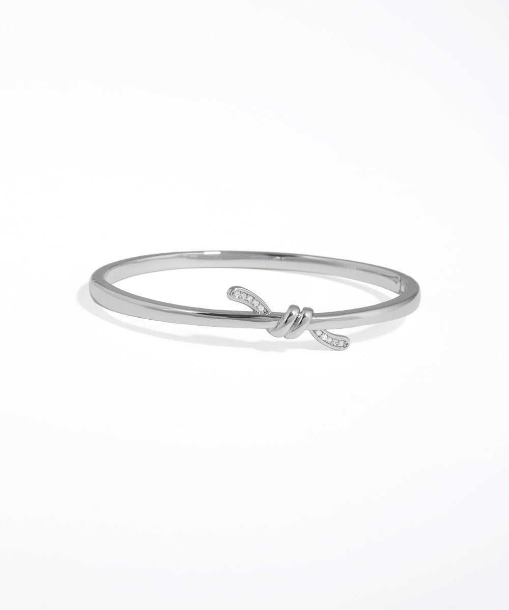 Silver bracelet with a knot design on a white background
