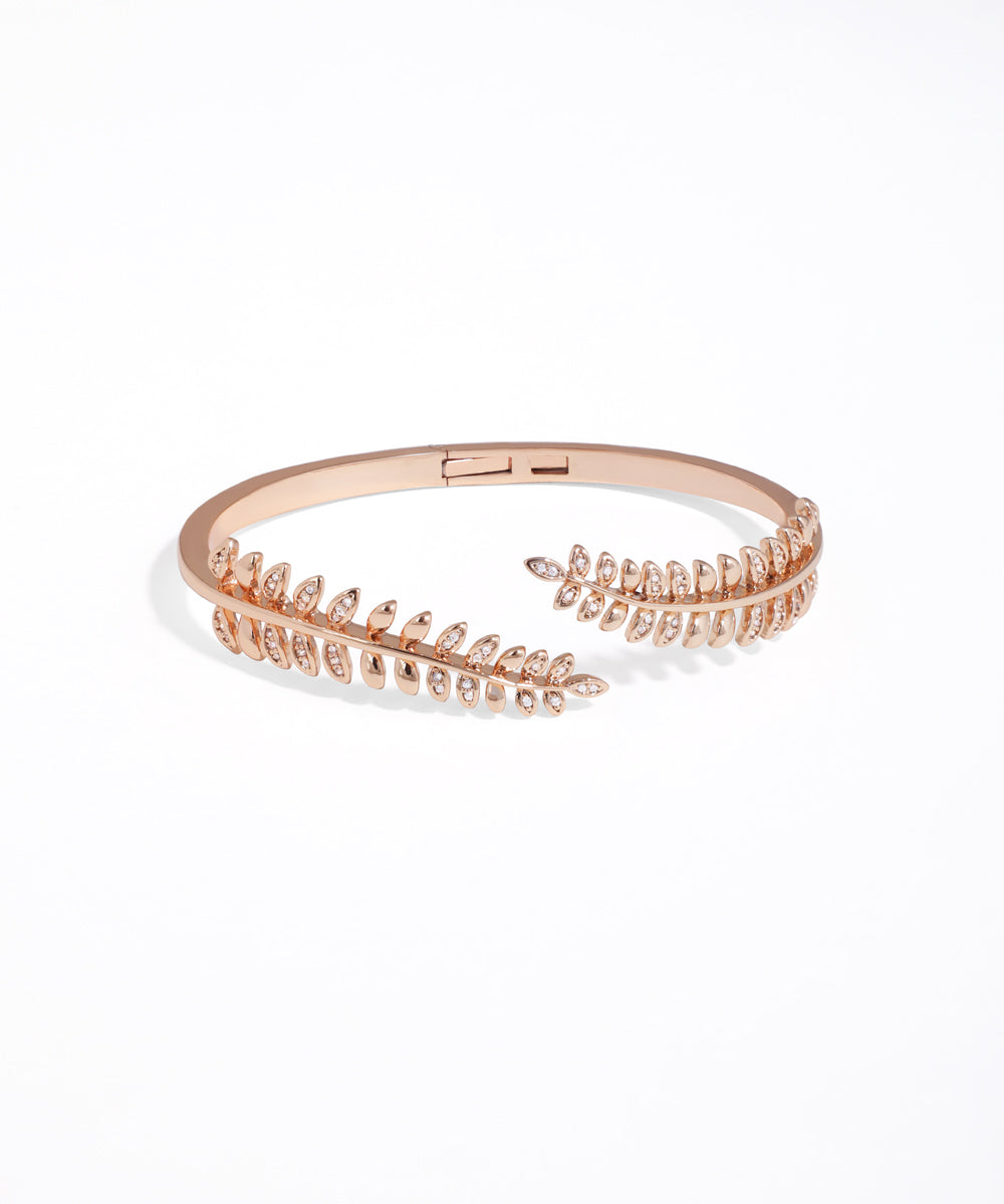 Rose gold bracelet with leaf-like design on a white background