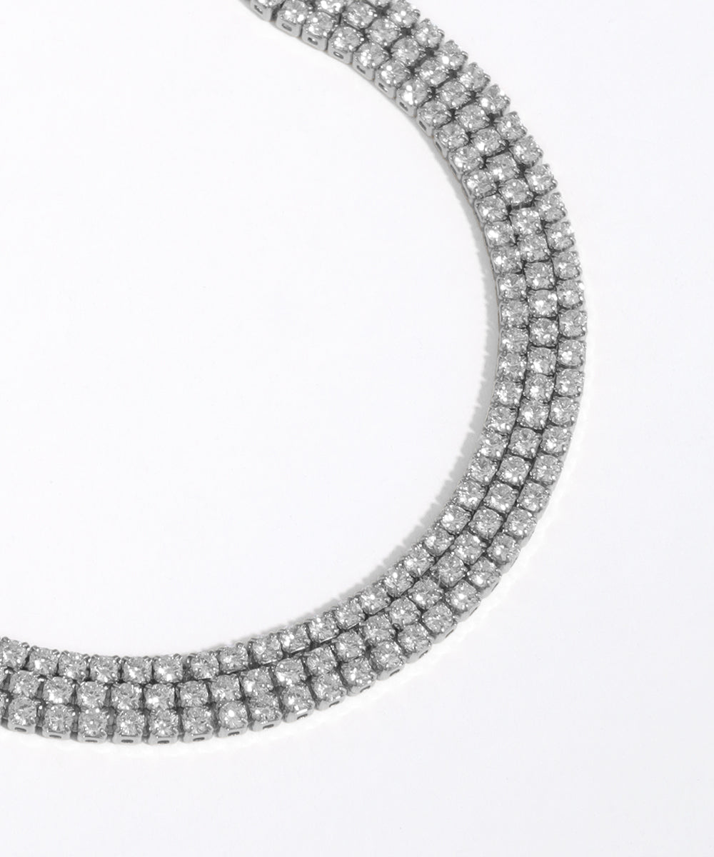 Close-up of a silver necklace with clear gemstones on a white background