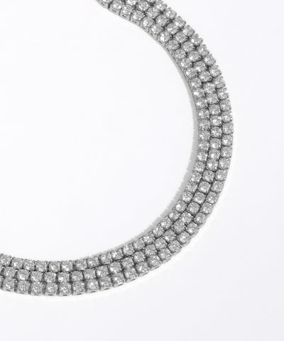 Close-up of a silver necklace with clear gemstones on a white background