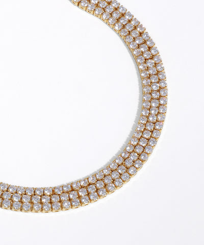 Gold necklace with clear gemstones on a white background