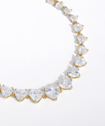 Gold necklace with heart-shaped clear gemstones on a white background