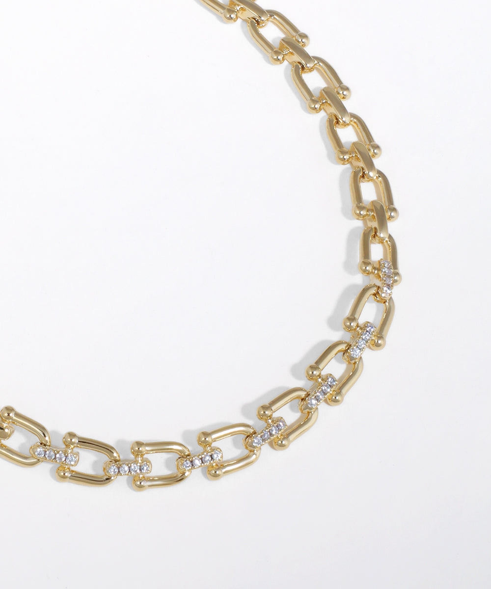 Gold chain necklace with diamond-like stones on a white background