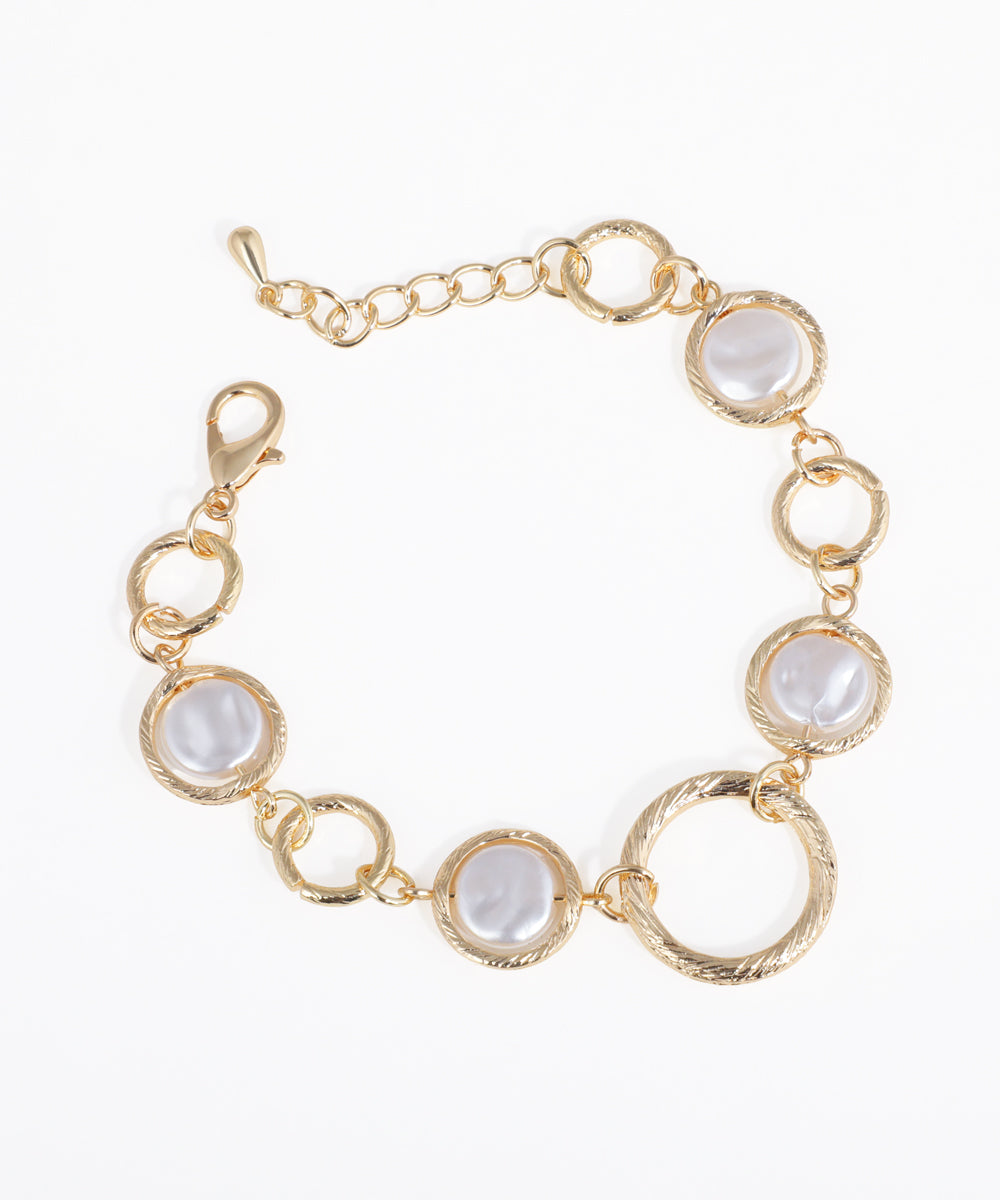 Gold-tone bracelet with textured link rings and flat, irregular faux pearls, secured with a lobster clasp.