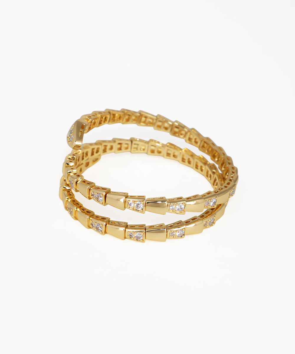 Set of gold bracelets with embedded stones on a white background
