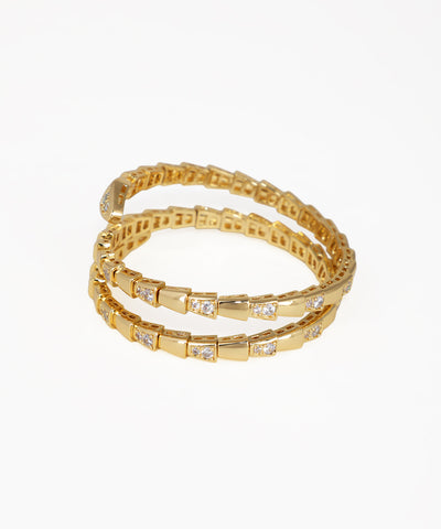 Set of gold bracelets with embedded stones on a white background